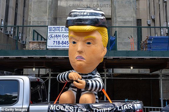 NEW YORK, NEW YORK - MAY 28: A person drives by Manhattan Criminal Court with an inflatable ballon depicting Former U.S. President Donald Trump in a jail uniform on May 28, 2024 in New York City. Closing arguments begin in former U.S. President Trump's hush money trial. The former president faces 34 felony counts of falsifying business records in the first of his criminal cases to go to trial.(Photo by David Dee Delgado/Getty Images)