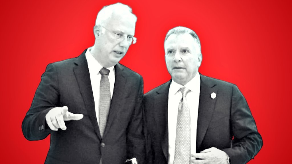 Two business professionals engaged in conversation against a vibrant red background, discussing important topics in a formal setting.