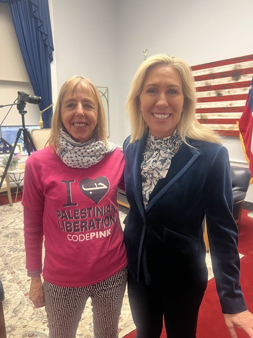 Two women pose together in a congressional office, one wearing a pink shirt with "Palestinian Liberation" text, highlighting activism and political engagement.