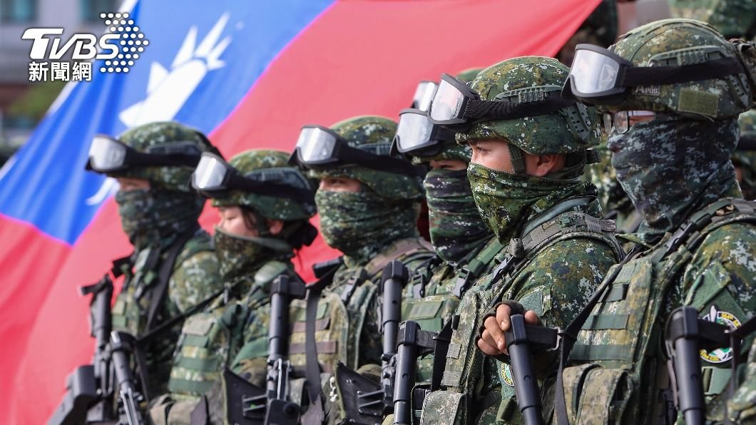 Taiwanese soldiers in camouflage gear stand in formation with weapons, showcasing military readiness against a backdrop of the national flag.