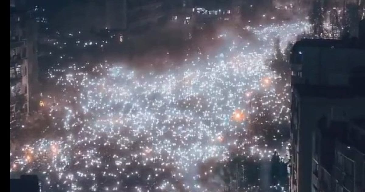 Aerial view of a densely packed crowd illuminated by numerous lights during a nighttime event, showcasing a vibrant atmosphere in an urban setting.