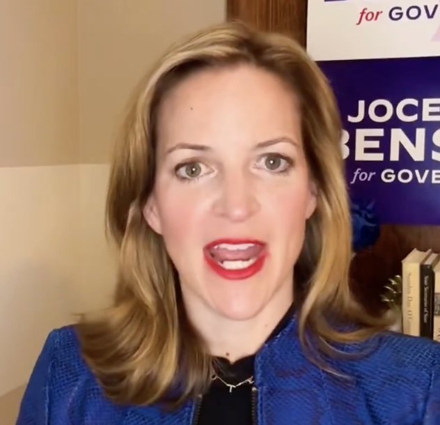 Jocelyn Benson, a political candidate, speaks passionately in front of her campaign sign, showcasing her commitment to running for governor.
