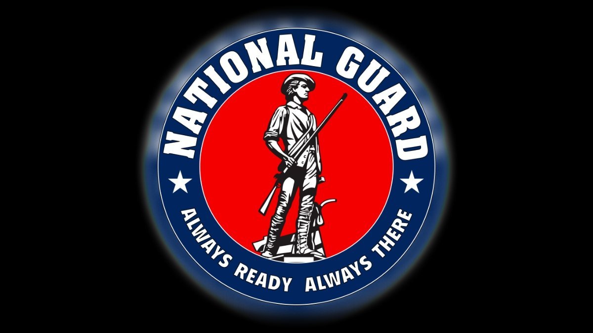 National Guard emblem featuring a soldier with a musket, surrounded by a circular blue and red design with the text "Always Ready Always There."