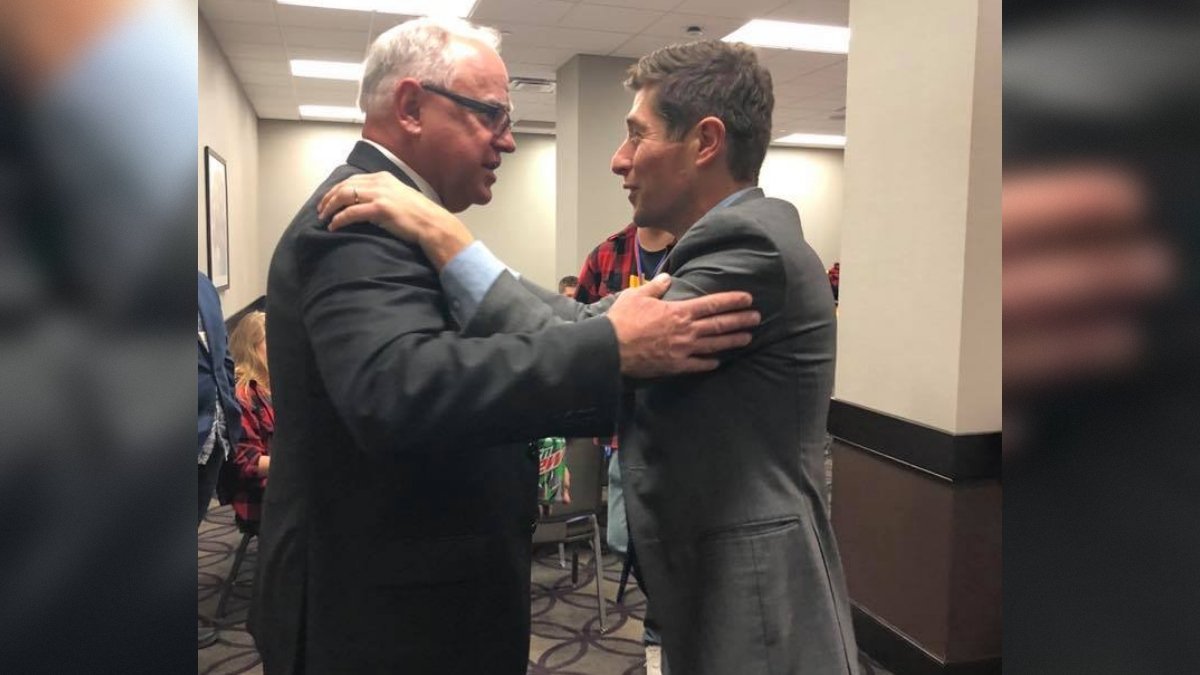 Two men in business attire engage in a friendly conversation at a gathering, showcasing camaraderie in a professional setting.
