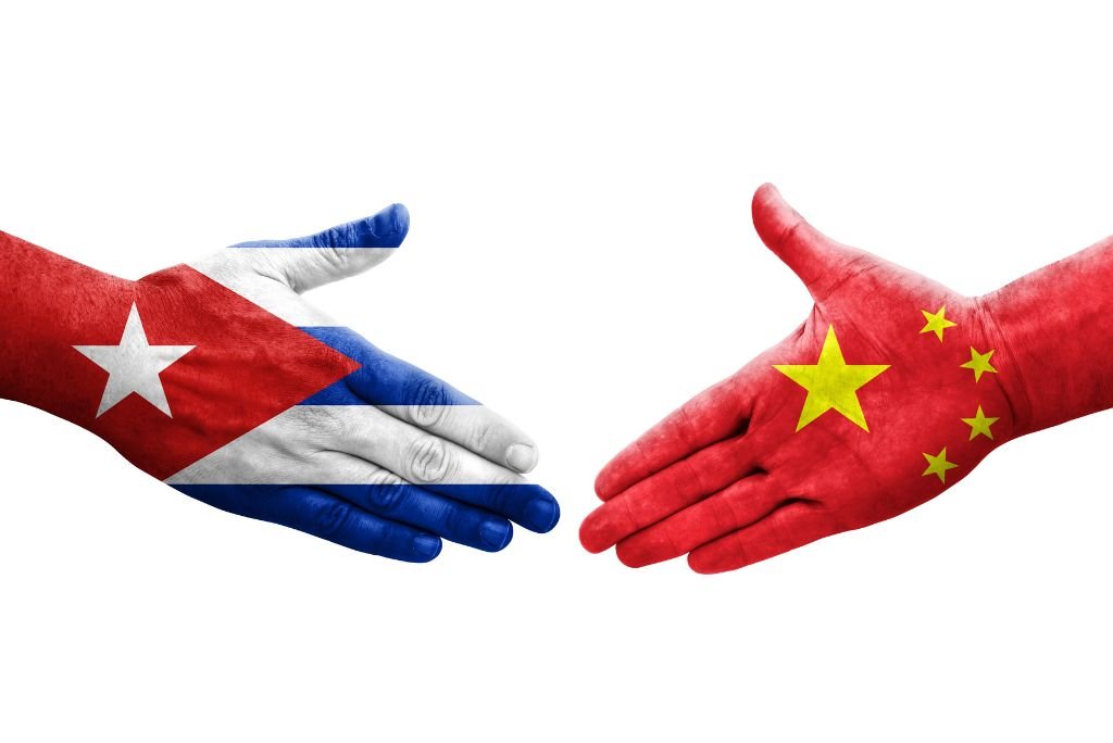 Hands painted with the flags of Cuba and China reaching out to each other, symbolizing friendship and cooperation between the two nations.