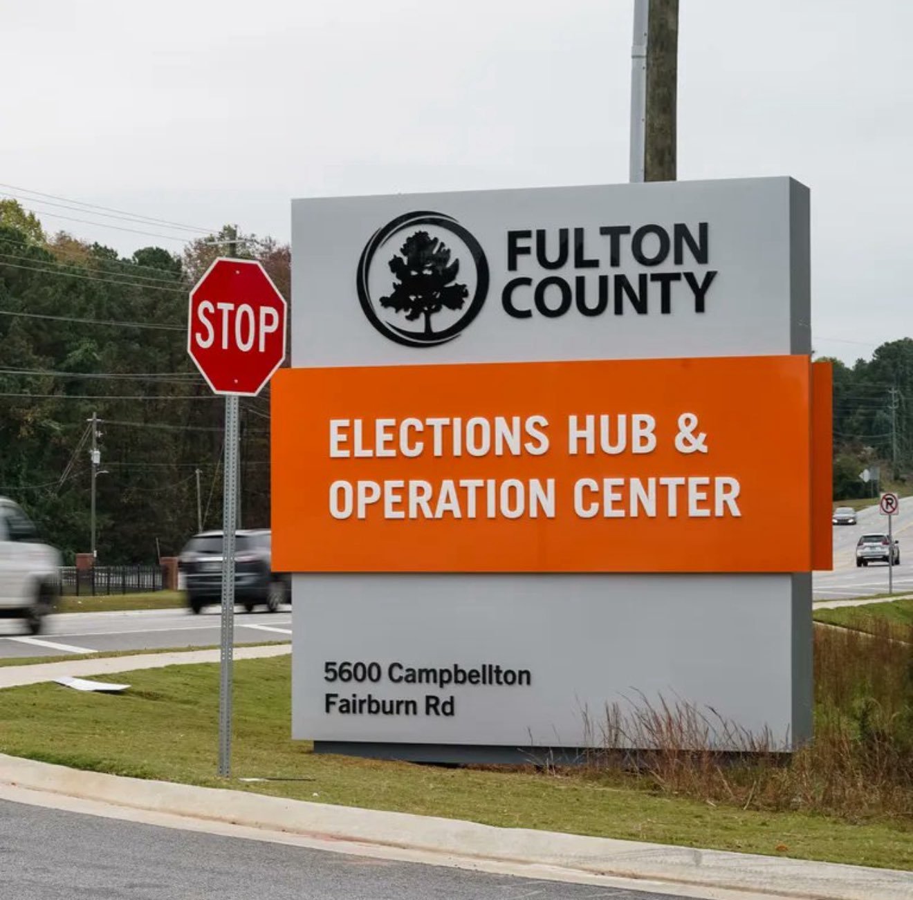 Fulton County Elections Hub and Operation Center sign at 5600 Campbellton Fairburn Road, featuring a stop sign and surrounding traffic.
