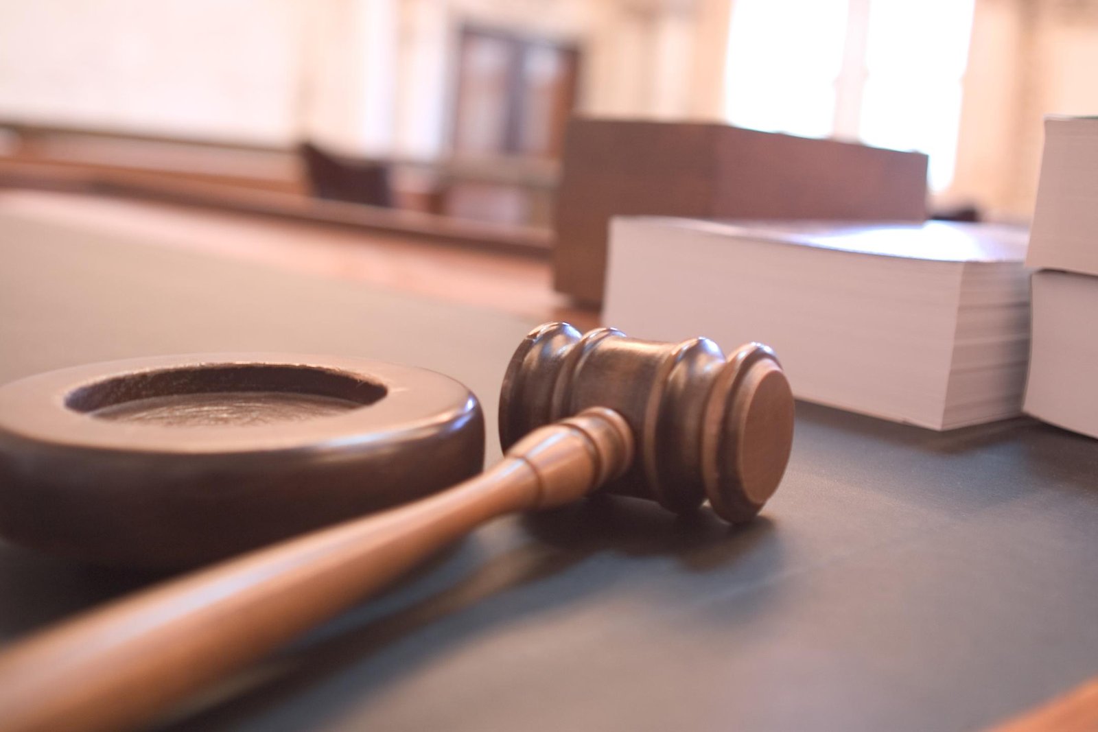 Close-up of a wooden gavel and sound block on a courtroom table, symbolizing justice and legal proceedings.