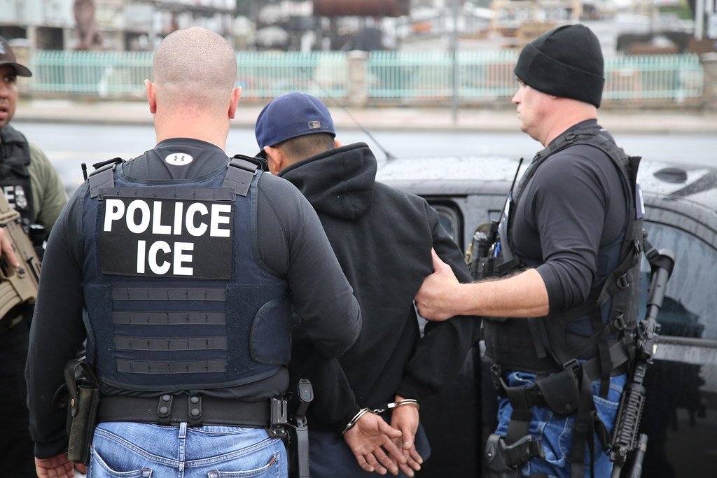 ICE officers apprehending a suspect during an enforcement operation, showcasing law enforcement activities in an urban setting.