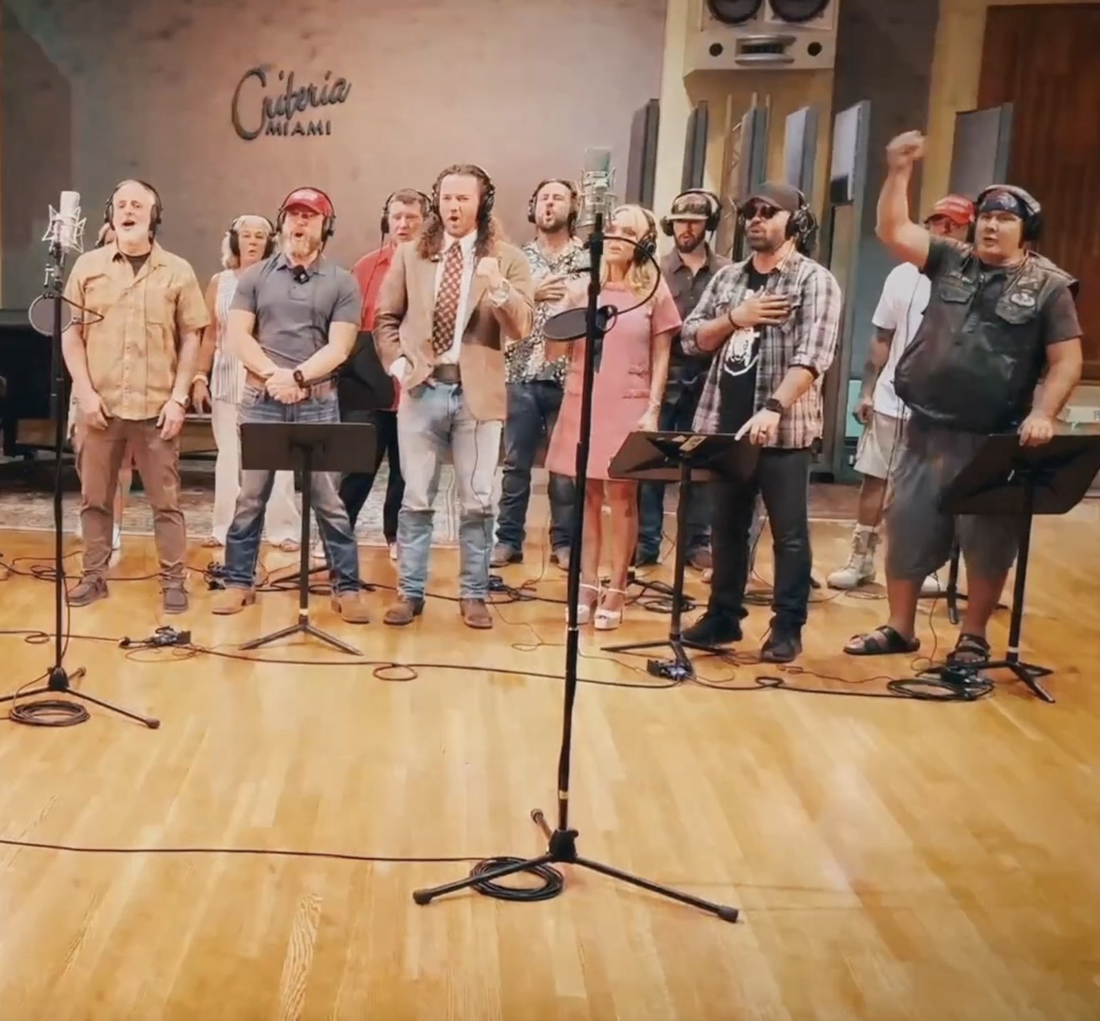 A diverse group of singers performing in a recording studio, surrounded by microphones and music stands, showcasing collaboration and musical talent.