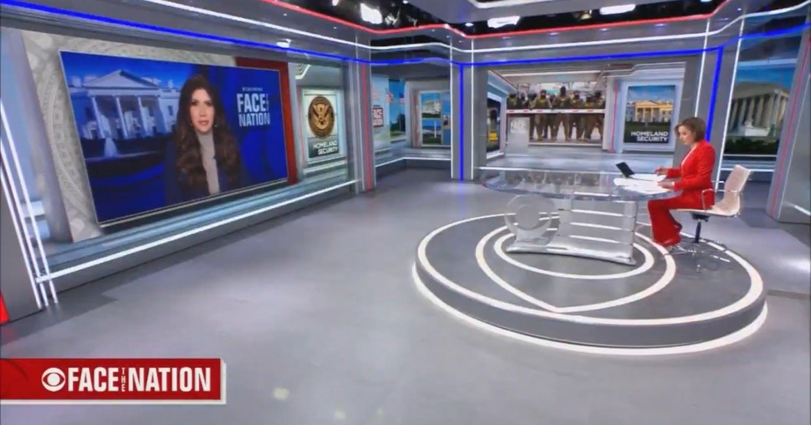 CBS Face the Nation studio featuring a host in a red outfit presenting news segments on a modern set with various screens and graphics.