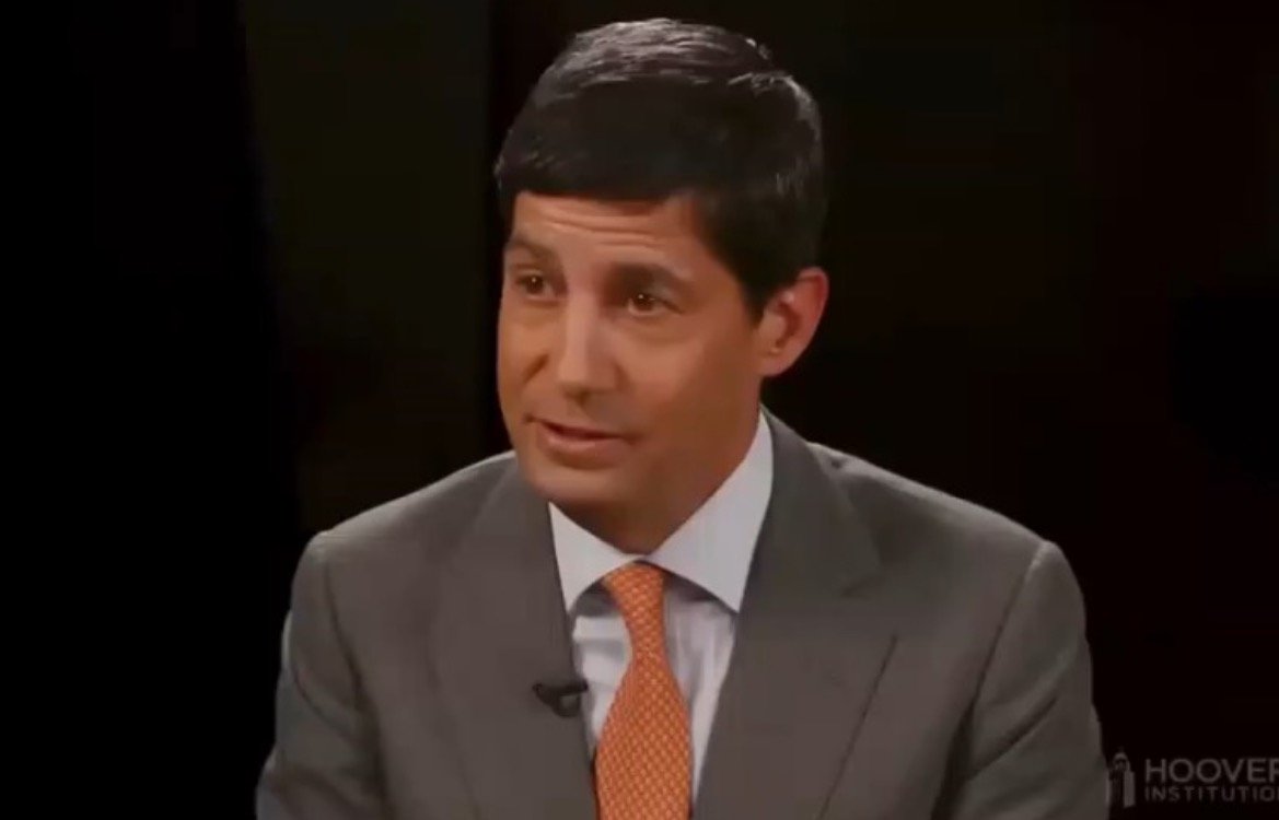 Business professional in a suit speaking during an interview at the Hoover Institution, focusing on economic and policy discussions.