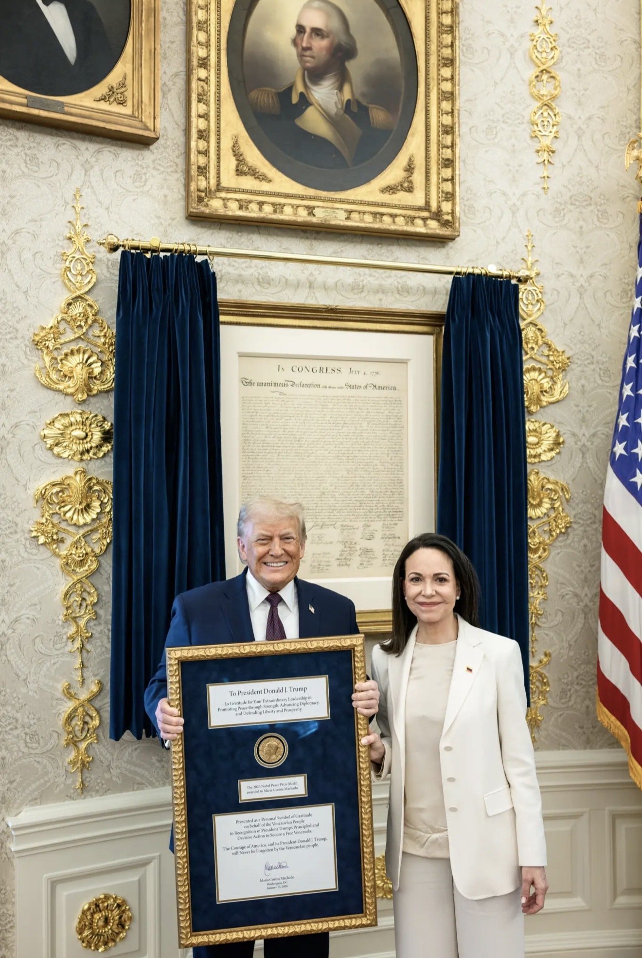 Former President Donald Trump and a woman hold a framed certificate in a decorated room featuring historical portraits and an American flag.