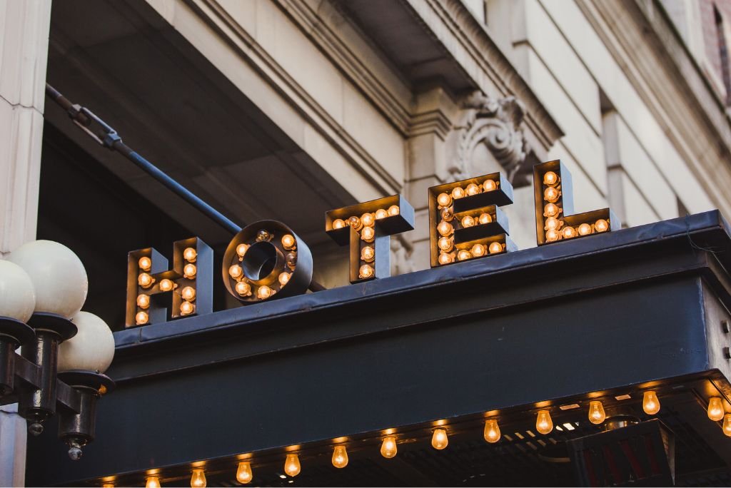 Vintage hotel sign with illuminated letters and decorative light bulbs, showcasing a classic architectural style.