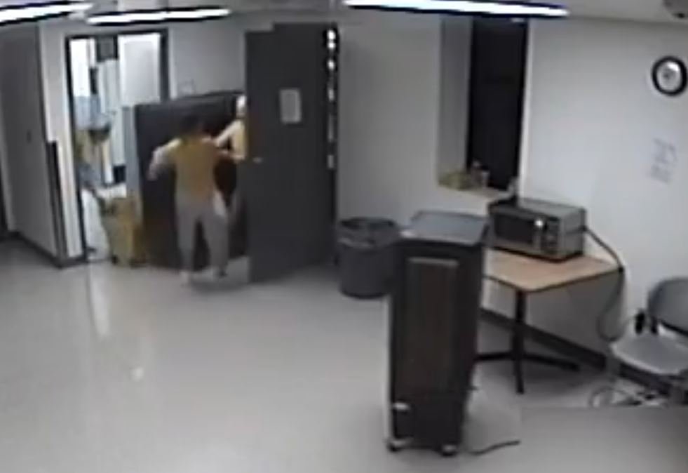 Surveillance footage captures two individuals entering a room with a microwave and a heater, highlighting an indoor setting with minimal furnishings.