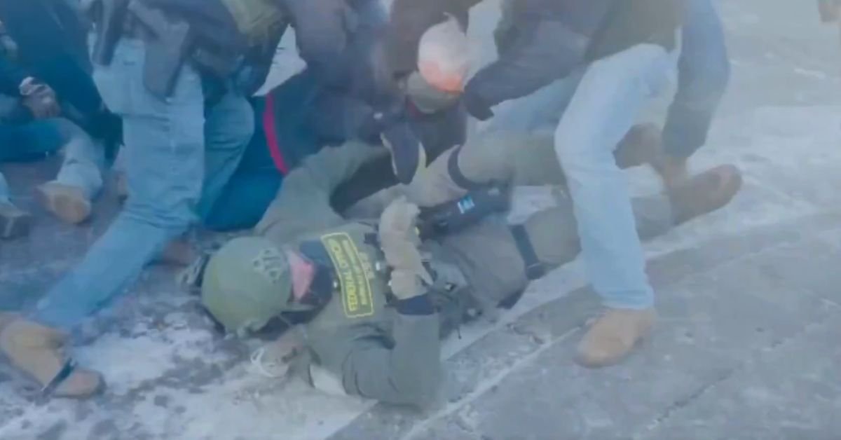Law enforcement officers apprehend a suspect during a chaotic scene, highlighting tensions in a public protest or conflict situation.