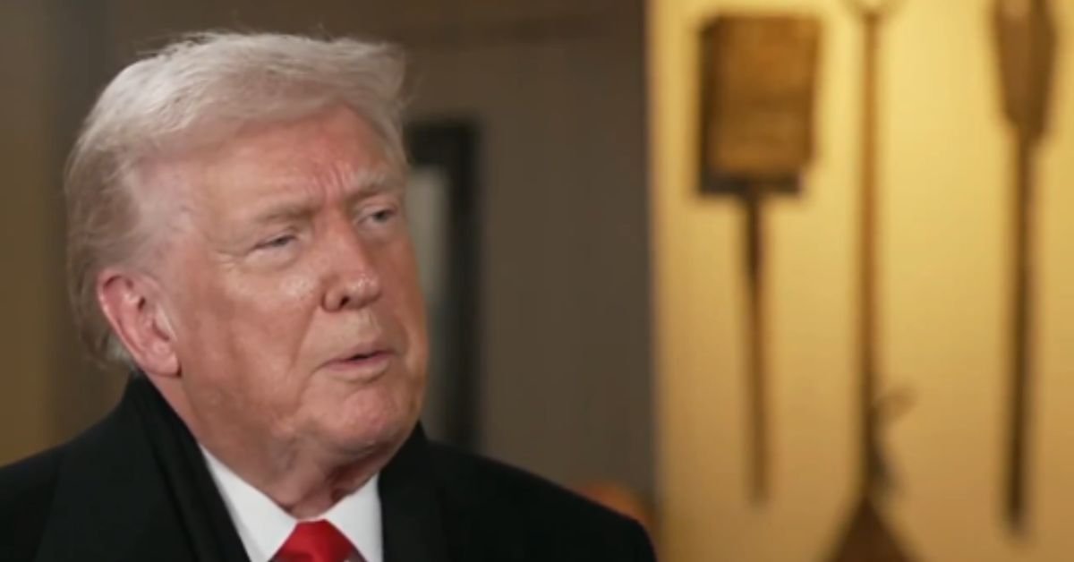 Donald Trump speaking during an interview, showcasing his signature hairstyle and formal attire against a blurred background.