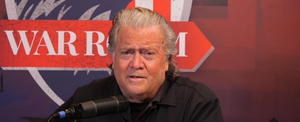 Steve Bannon speaking on the War Room podcast, discussing political issues with a microphone in front of him.
