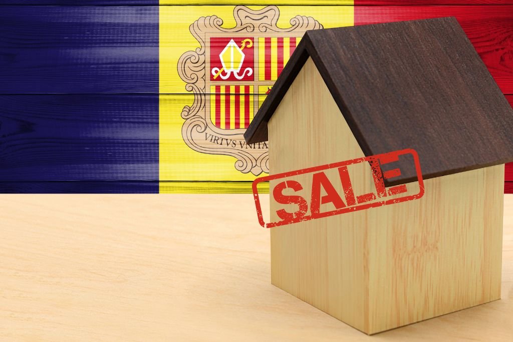 Wooden house model with a "SALE" stamp in front of the Andorra flag, symbolizing real estate opportunities in Andorra.