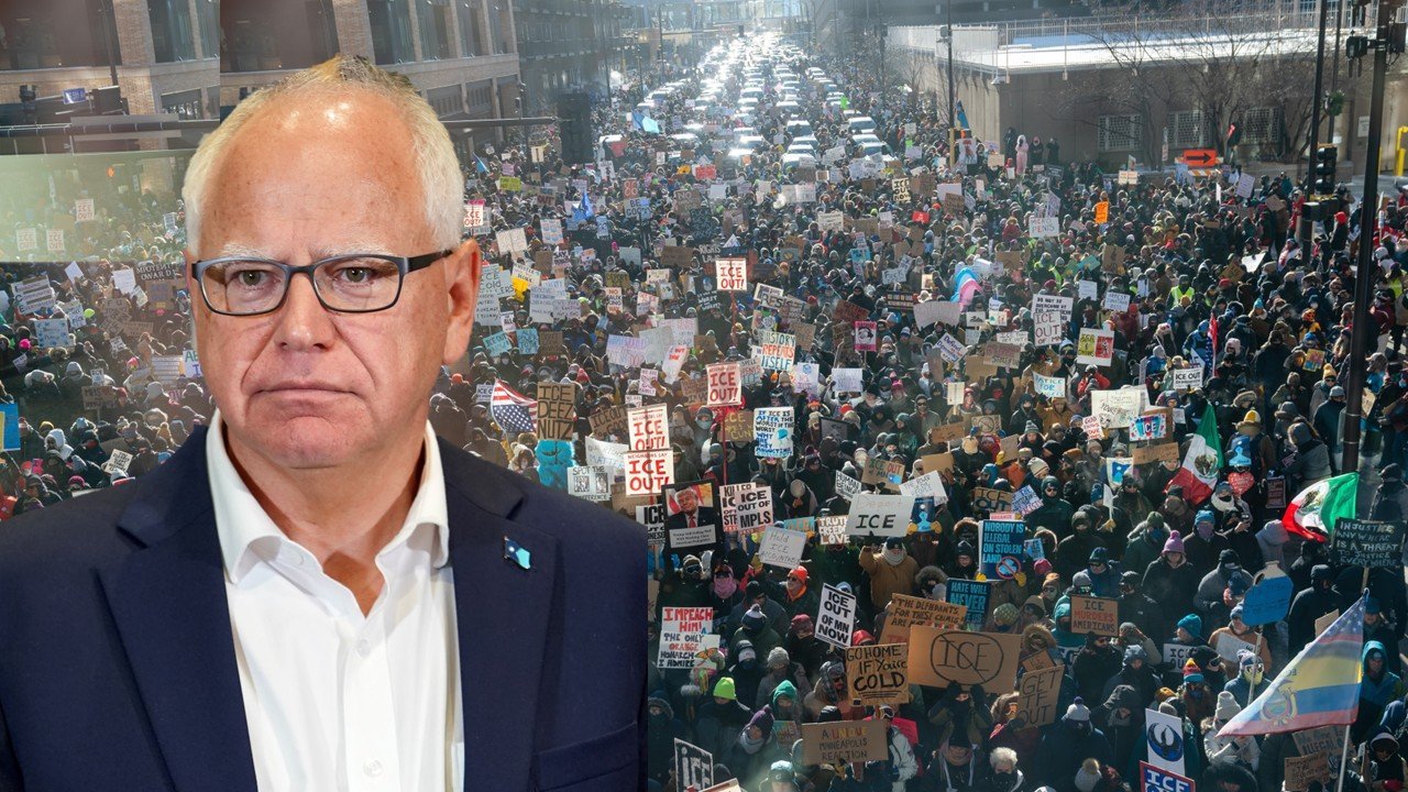 Crowd of protesters holding signs against ICE, with a serious-looking man in a suit in the foreground, advocating for immigration reform.