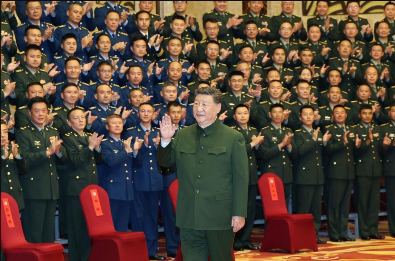 Chinese President Xi Jinping greets military personnel during a ceremony, surrounded by applauding officers in uniforms, showcasing support and unity within the armed forces.