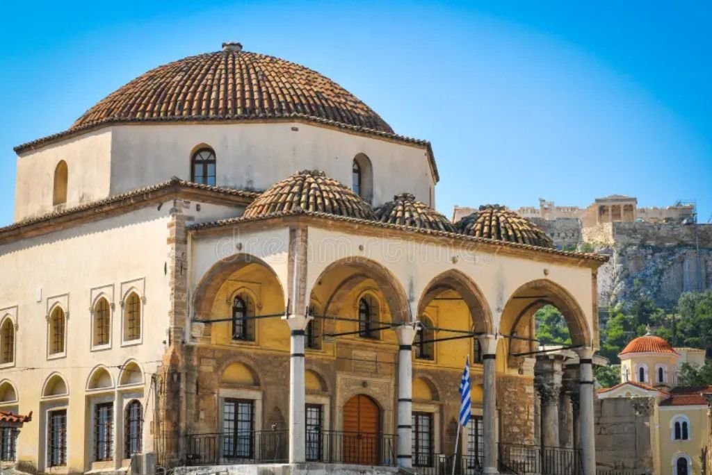 Historic Byzantine church with a domed roof and arched columns, located in Athens, Greece, showcasing traditional architecture against a clear blue sky.