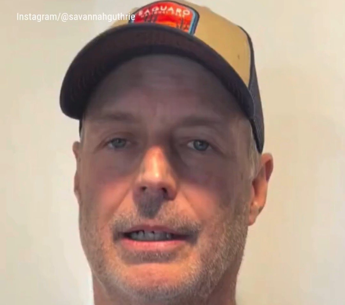 Man wearing a baseball cap with a vintage logo, looking directly at the camera against a plain background.
