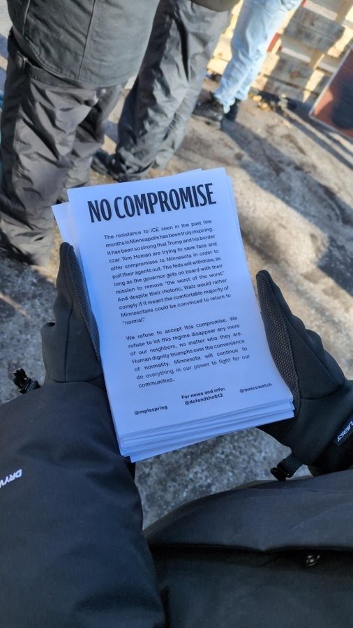 A person holding a printed flyer titled "No Compromise," addressing resistance to ICE and advocating for community rights during a protest.