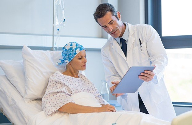 Doctor discussing treatment options with a cancer patient in a hospital room, highlighting patient care and medical consultation.