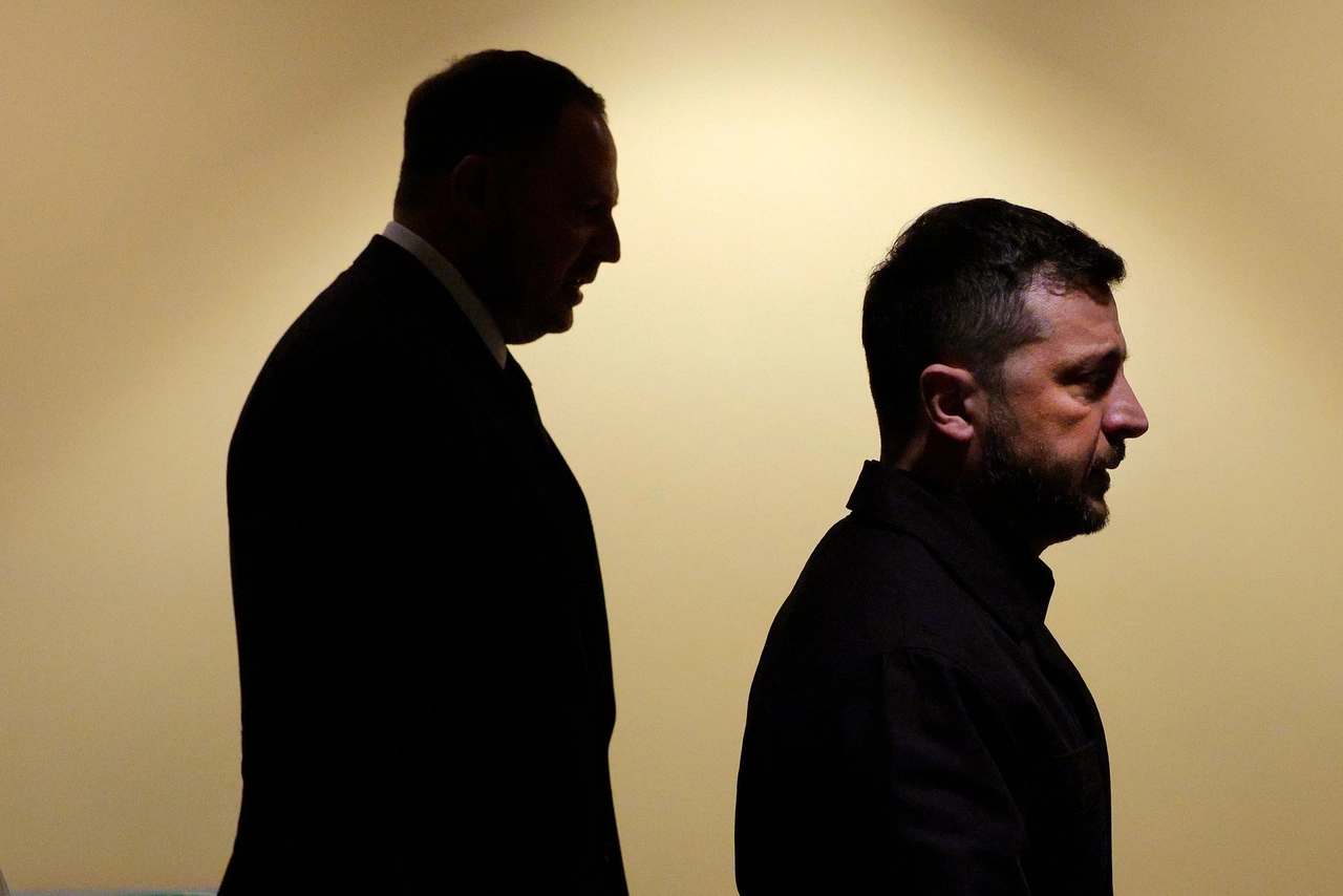 Silhouettes of two men in profile against a soft, neutral background, conveying a sense of tension and intrigue.